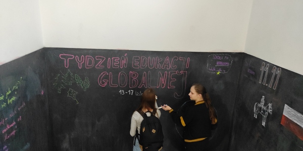 Dziewczynki piszą informację o TEG na ścianie klatki schodowej