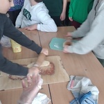 Dwóch uczniów wałkuje ciasto, a kilka osób się przygląda