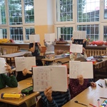Uczniowie pokazują swoje zeszyty z działaniami matematycznymi