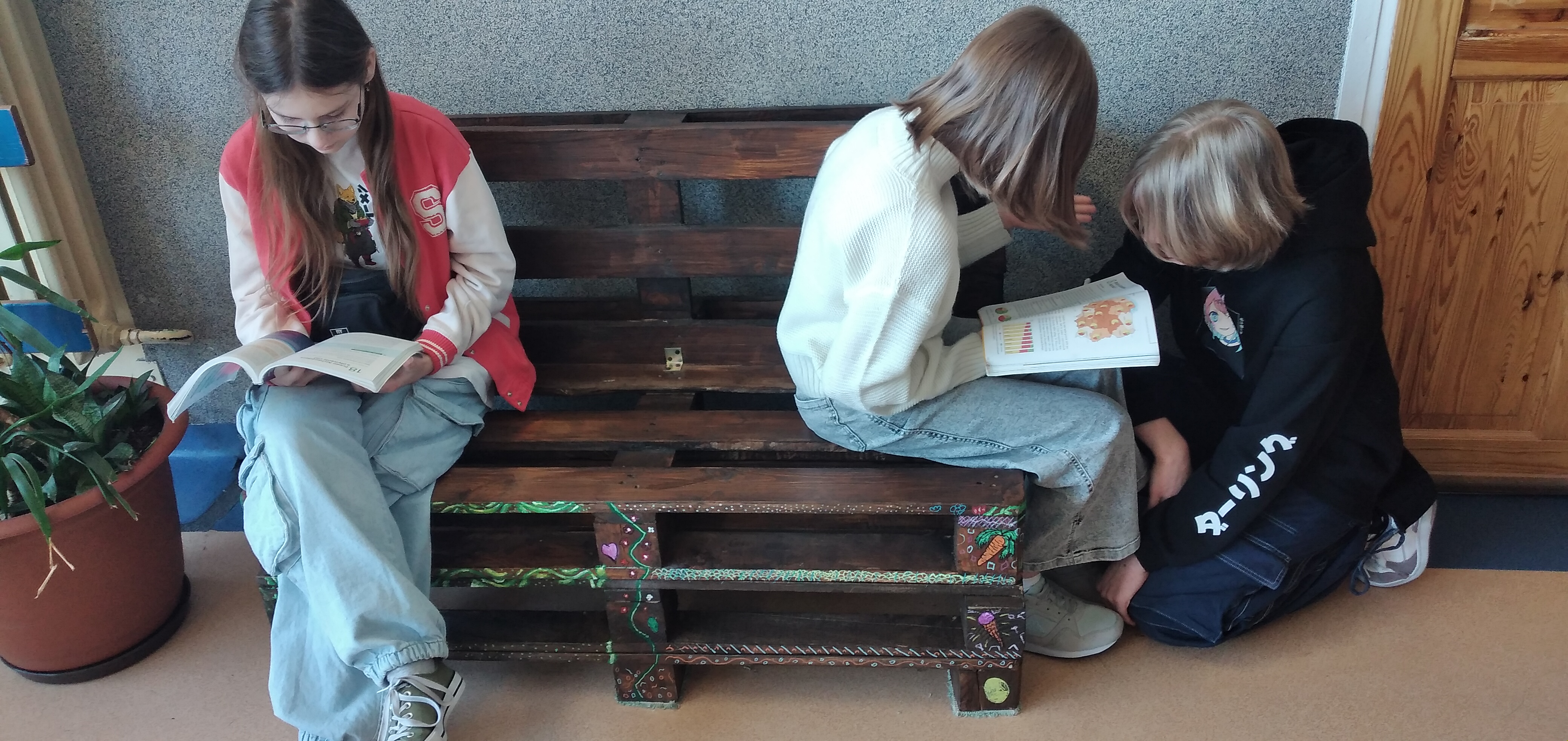 Uczennice na samodzielnie wykonanej ławeczce z palet