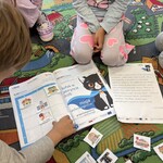 Uczniowie nachyleni nad książeczką do programu